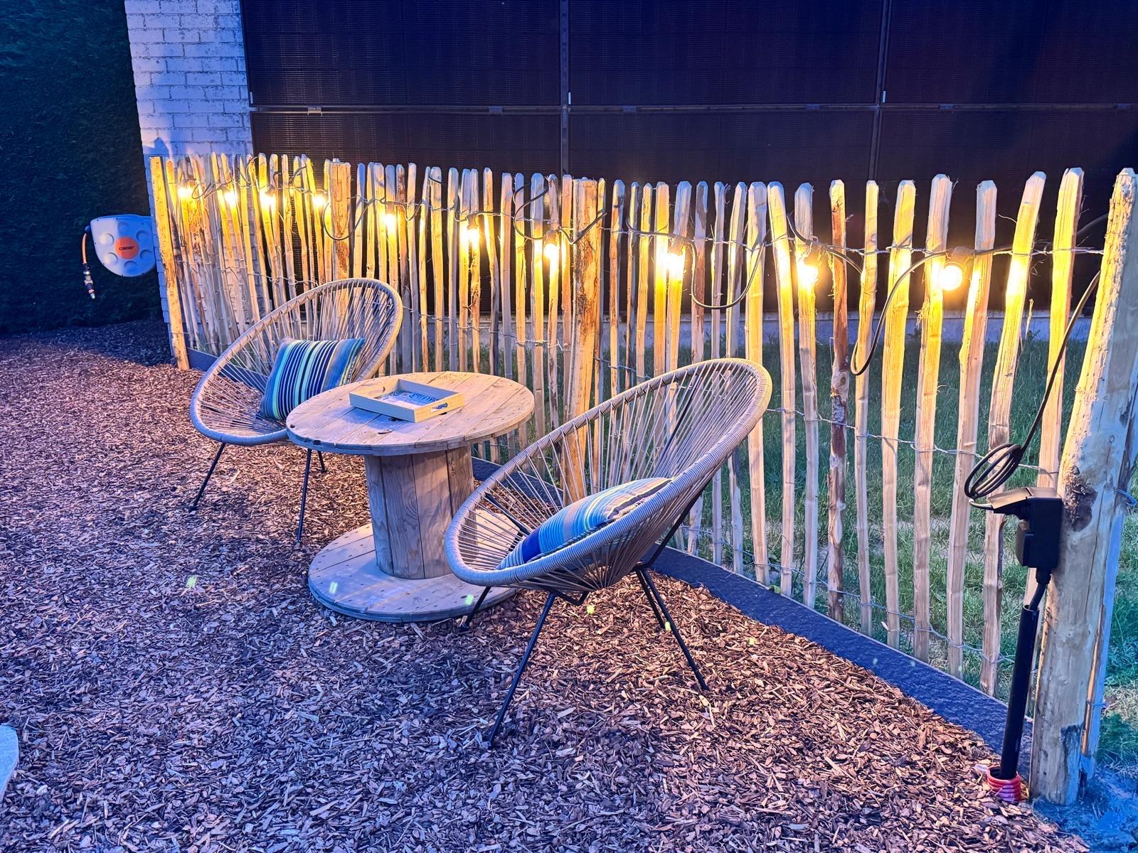 Gezellige loungehoek met lichtsnoer in de tuin
