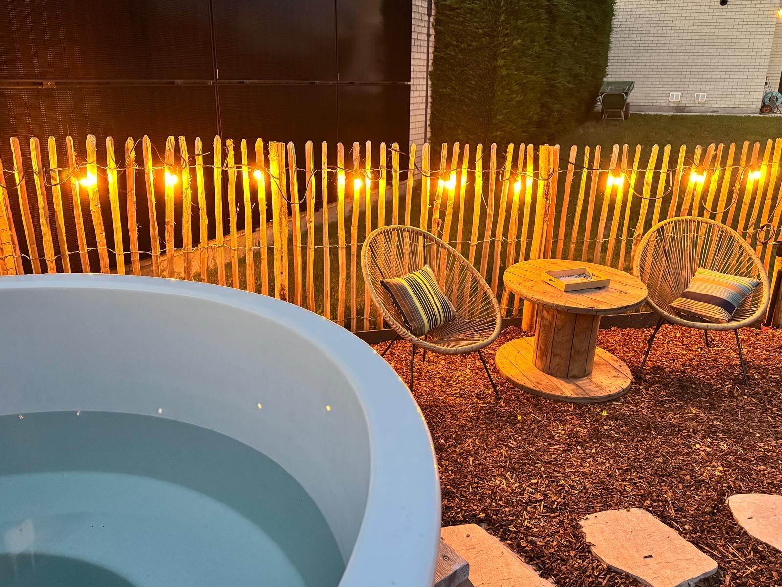 Hot tub en loungehoek met lichtsnoer bij avond