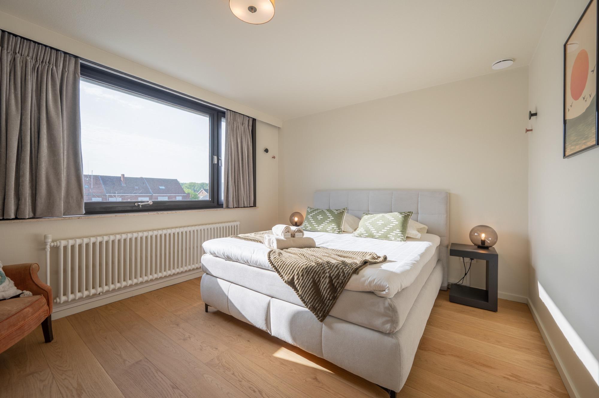 Slaapkamer met boxspring en groene kussens