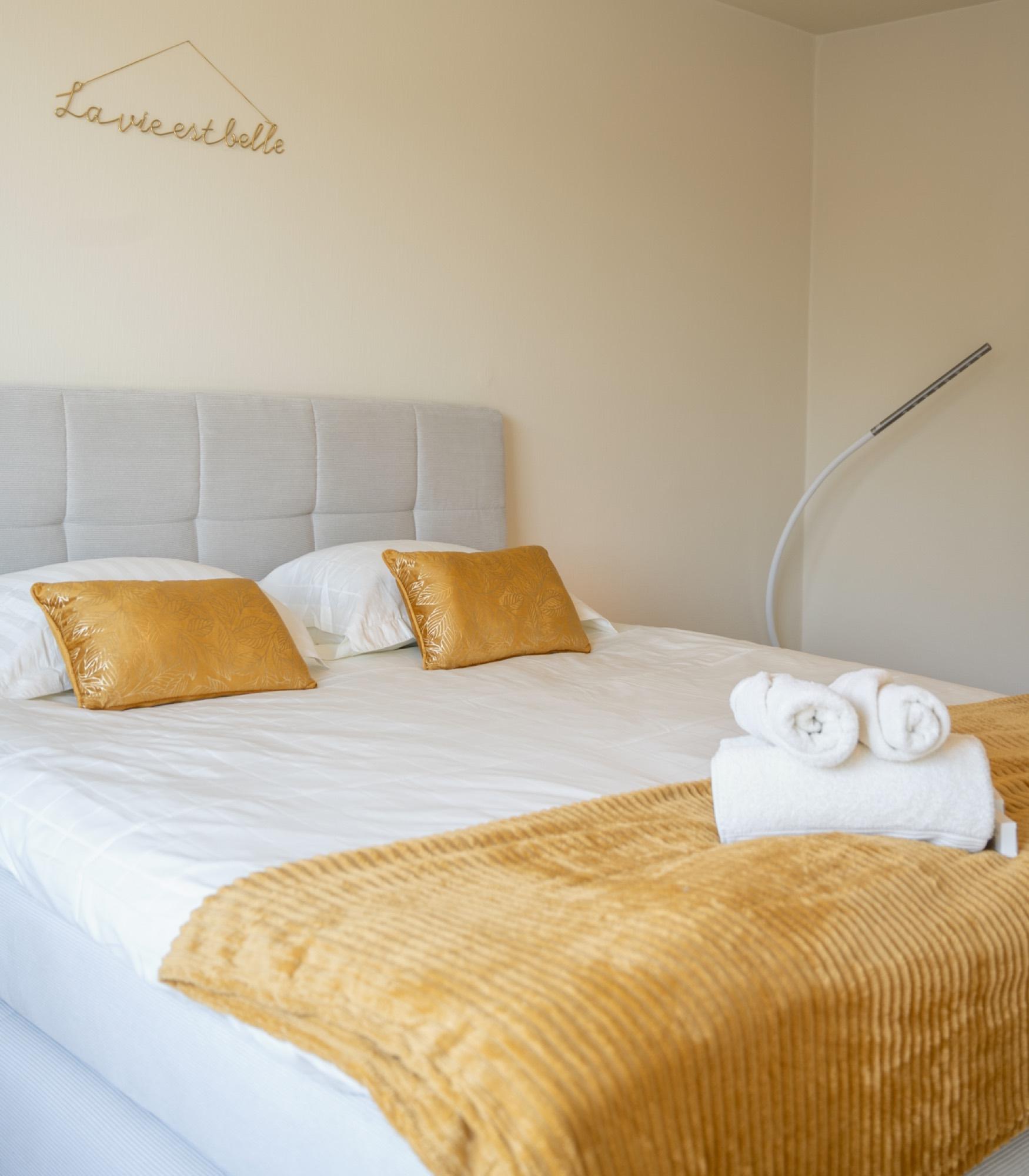 Detail van bed met okergele kussens