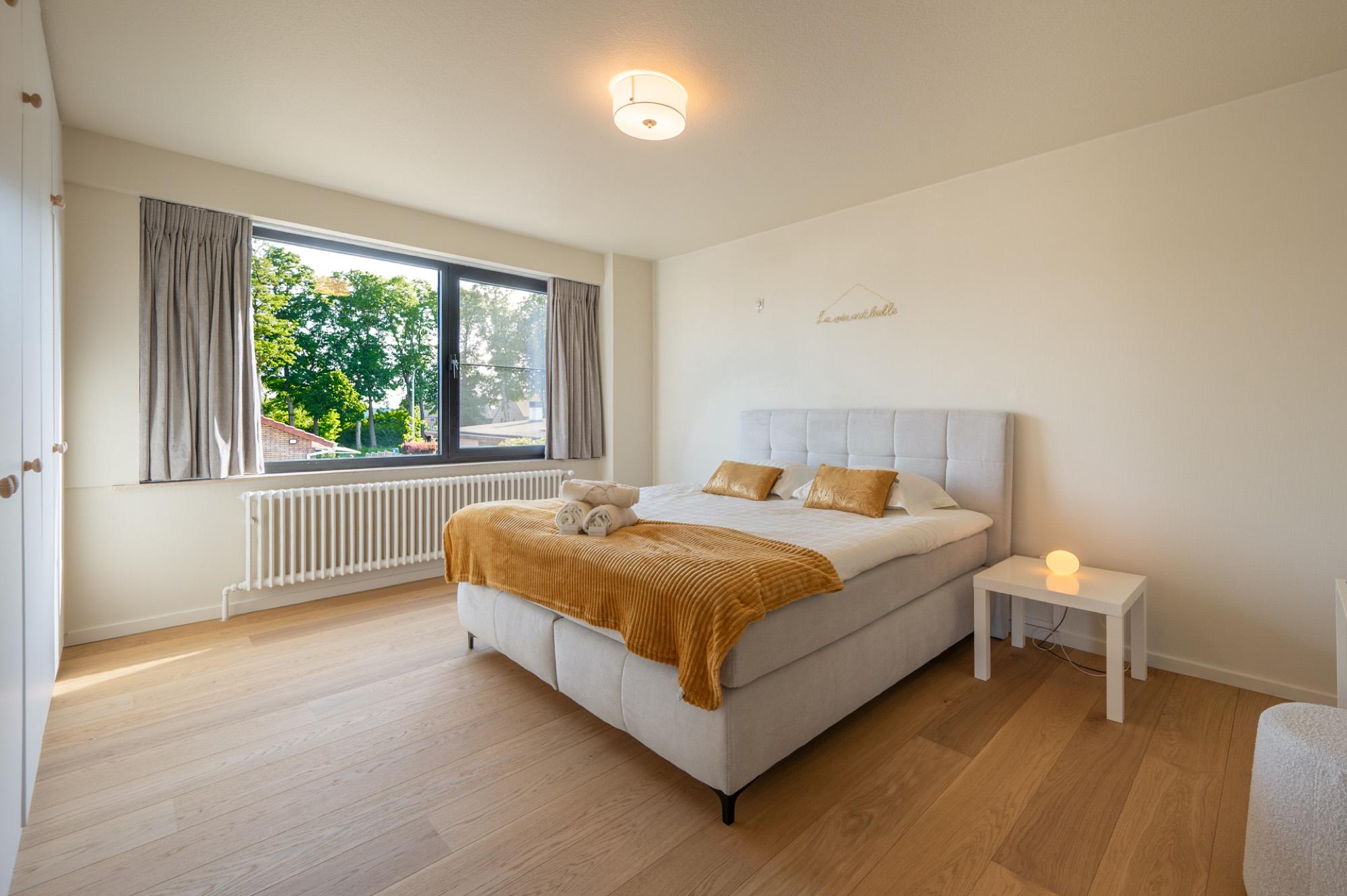 Slaapkamer met boxspring en okergele plaid